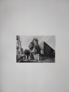 Eine schwarz-weiß Fotografie an einer Wand. Sie zeigt die Ecke eines Industriegebäudes.