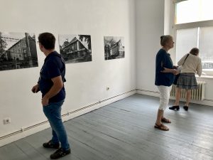 Menschen betrachten in einer Ausstellung die Fotografien von Hacer Bozkurt. Sie zeigen Ausschnitte von Gebäudefassaden.
