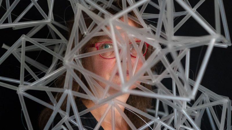 Portrait der Künstlerin Angelika Höger. Ihr Kopf ist von einer geometrischen Skulptur verdeckt.