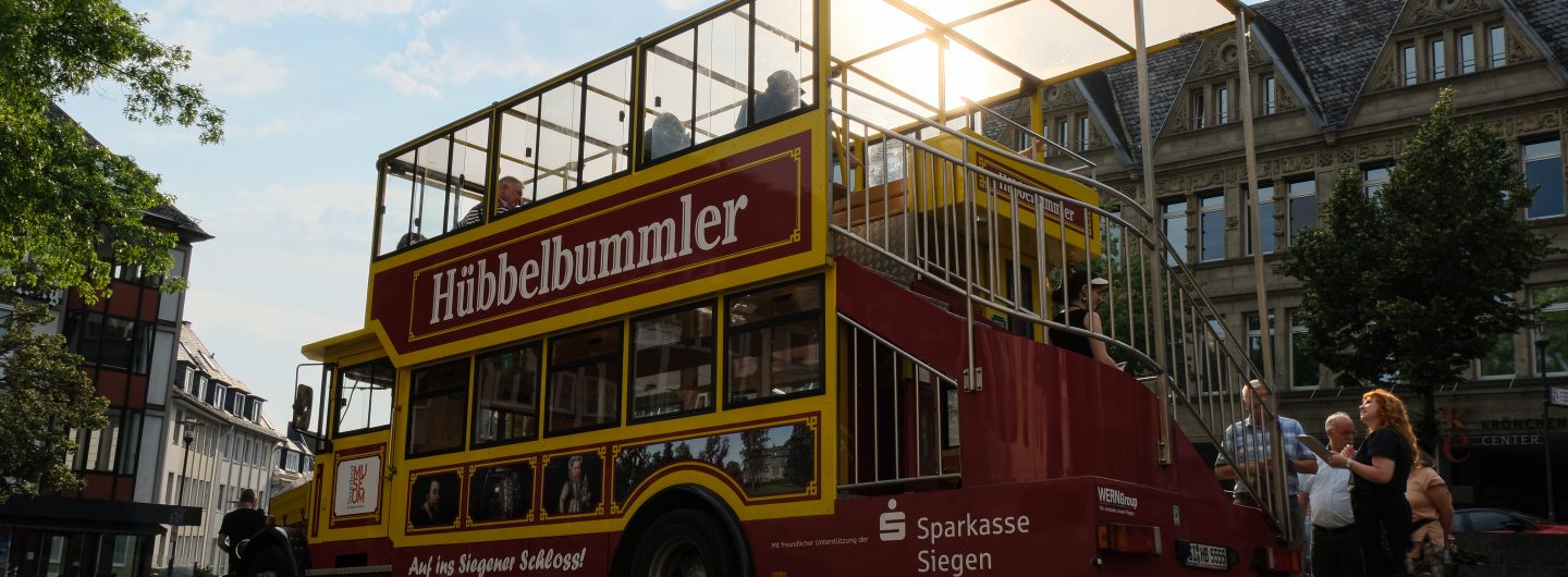 Der Hübbelbummler-Doppeldecker steht bei Sonnenuntergang in der Innenstadt Siegens.