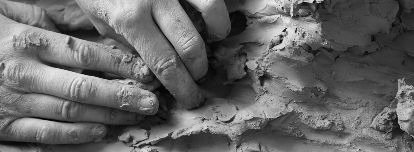 Schwarz-weiß Bild mehrerer Hände, die in Ton greifen.