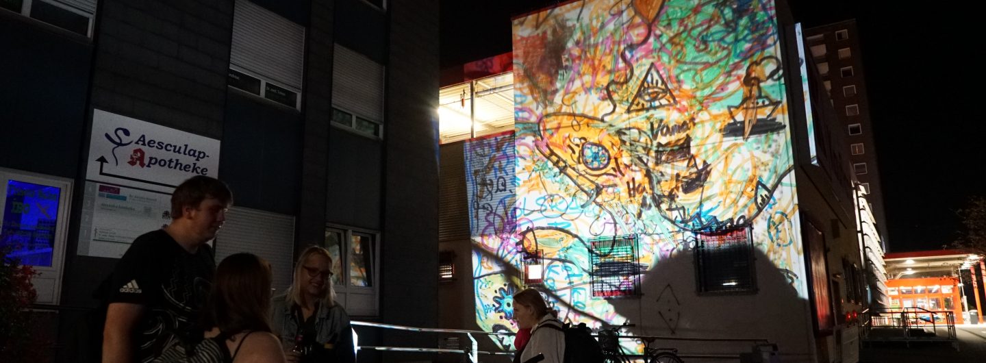 Auf eine Wand wird ein buntes Kunstwerk projiziert.